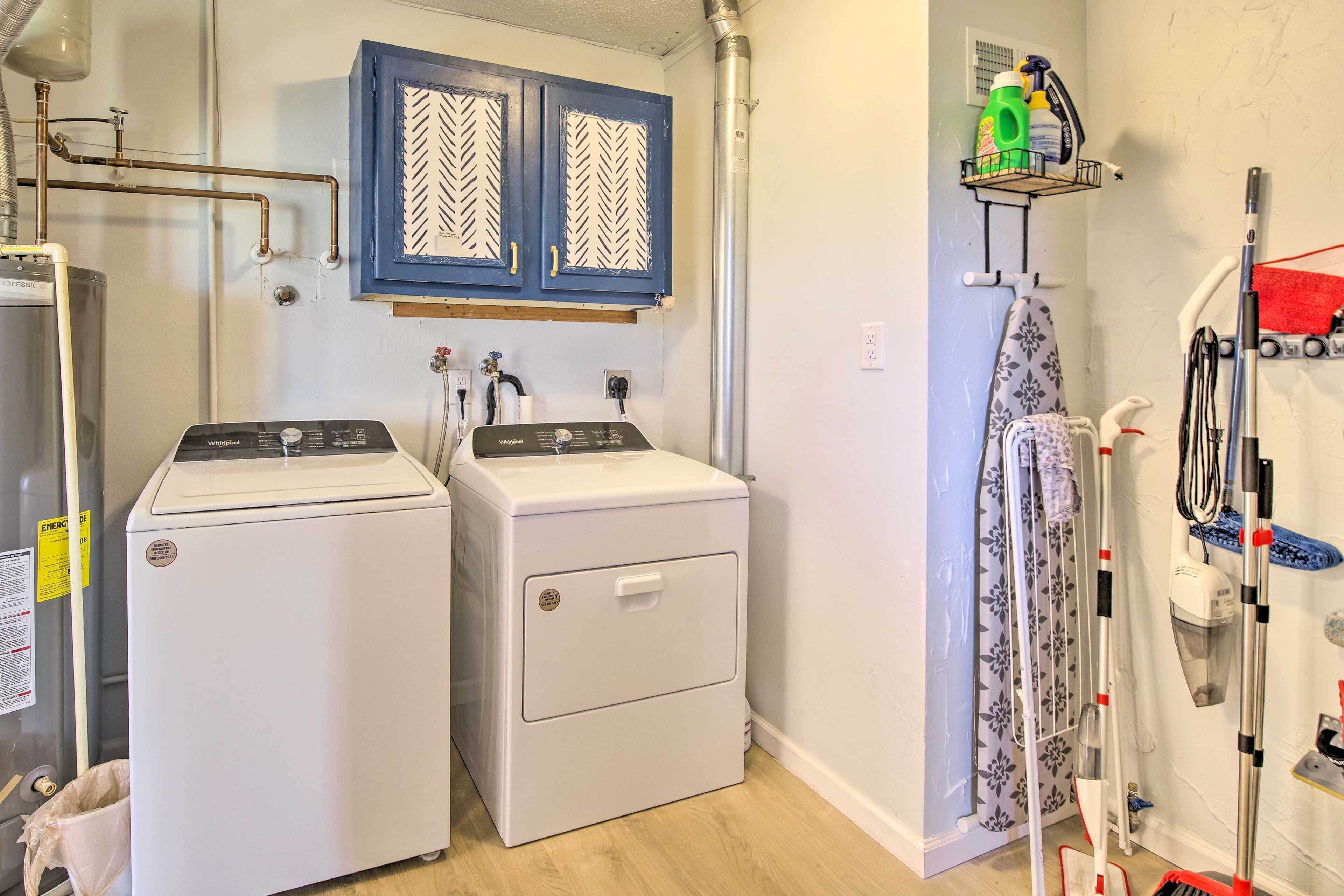 A laundry room with two front-loading washing machines, a steam iron, and a drying rack.