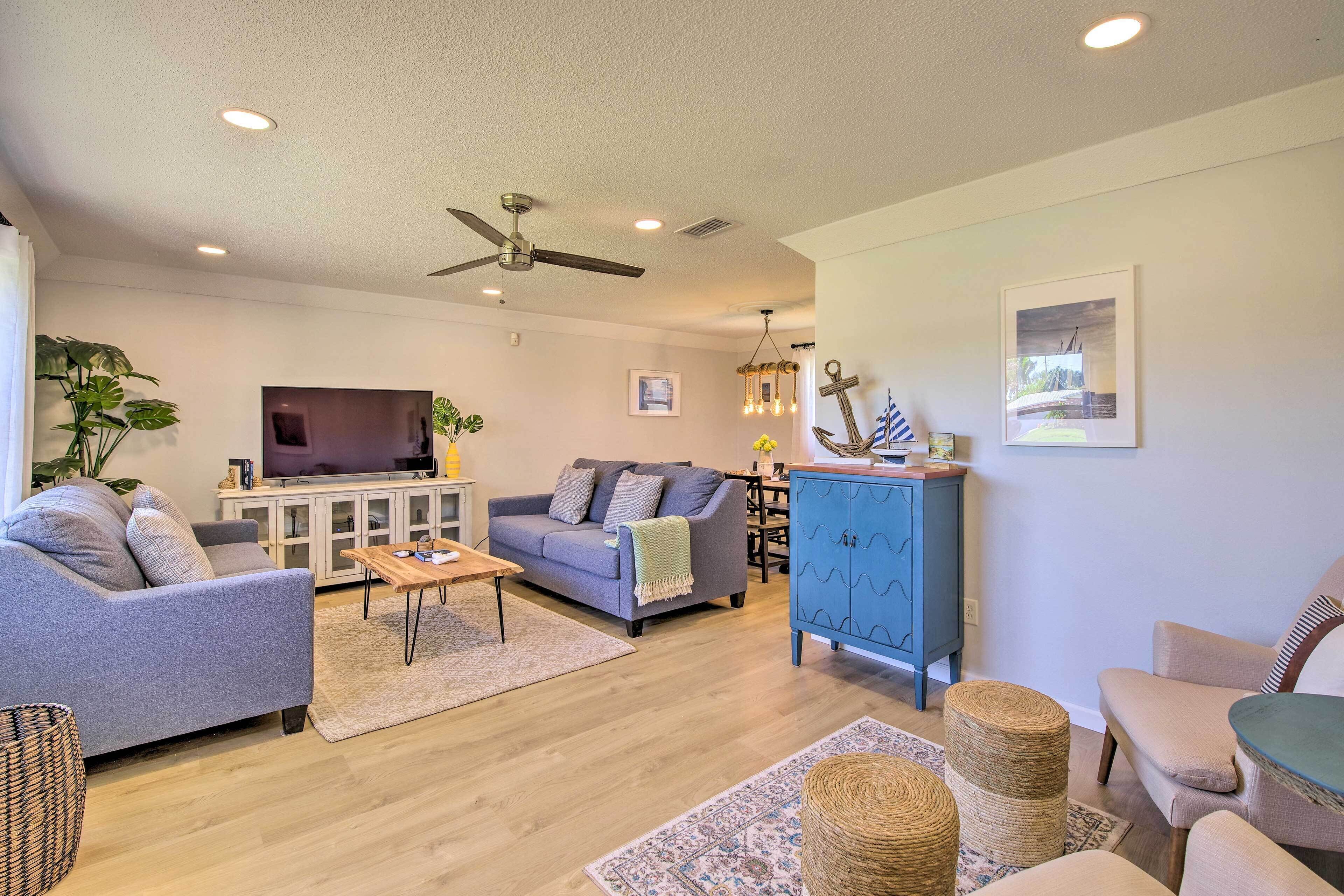 A modern living room with a grey sofa, a blue cabinet, a wooden coffee table, and a ceiling fan.