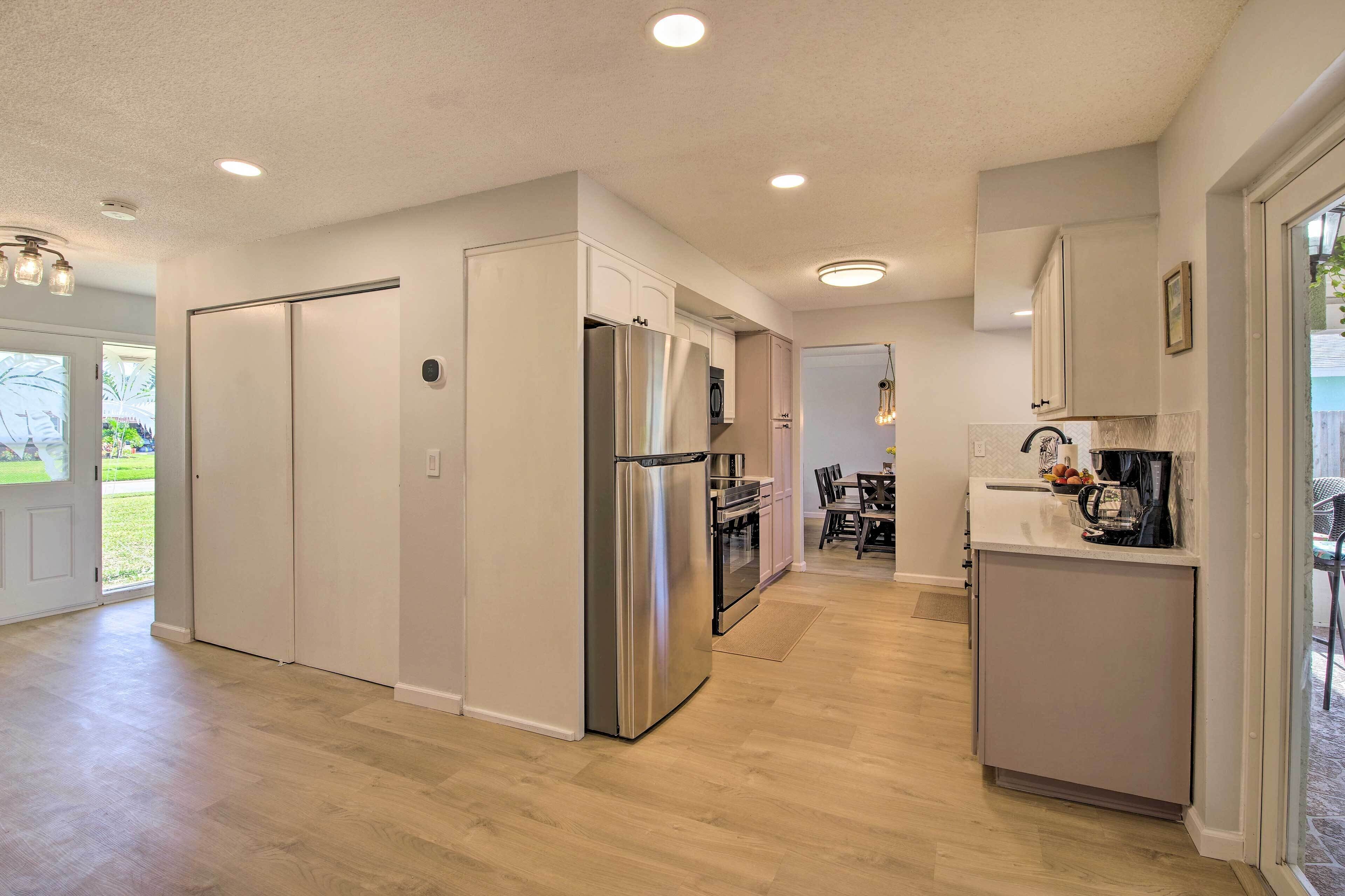 A modern kitchen with stainless steel appliances, a dining area with a table and chairs, and a view of the outdoors.