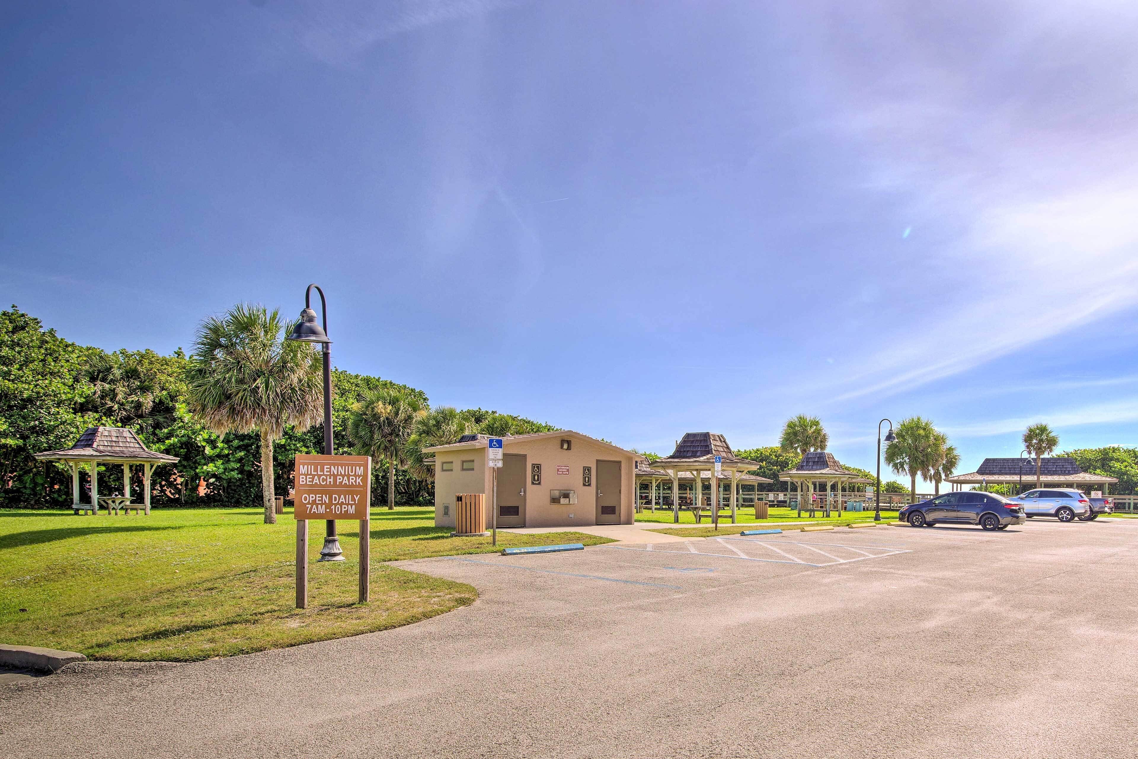 A parking lot with a sign for Millennium Beach Park, open daily from 7 AM to 10 PM.