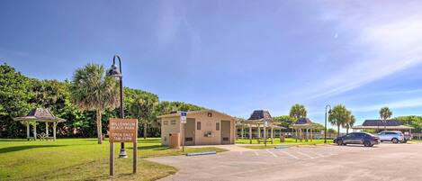 A parking lot with a sign for Millennium Beach Park, open daily from 7 AM to 10 PM.