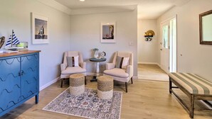 A living room with a blue cabinet, two armchairs, a bench, a patterned rug, and two small stools.