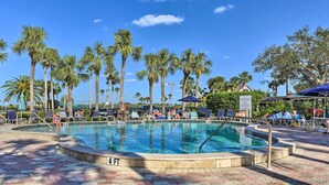 A pool area with palm trees, lounge chairs, and a sign indicating pool rules.