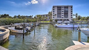 A marina with boats docked, a large building in the background, and a clear sky.