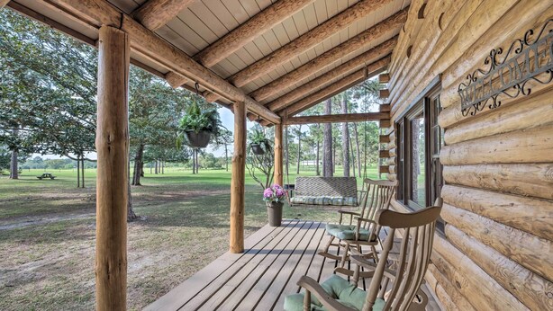 Une cabane en bois avec une véranda, des bancs en bois, des jardinières suspendues et une pancarte de bienvenue.