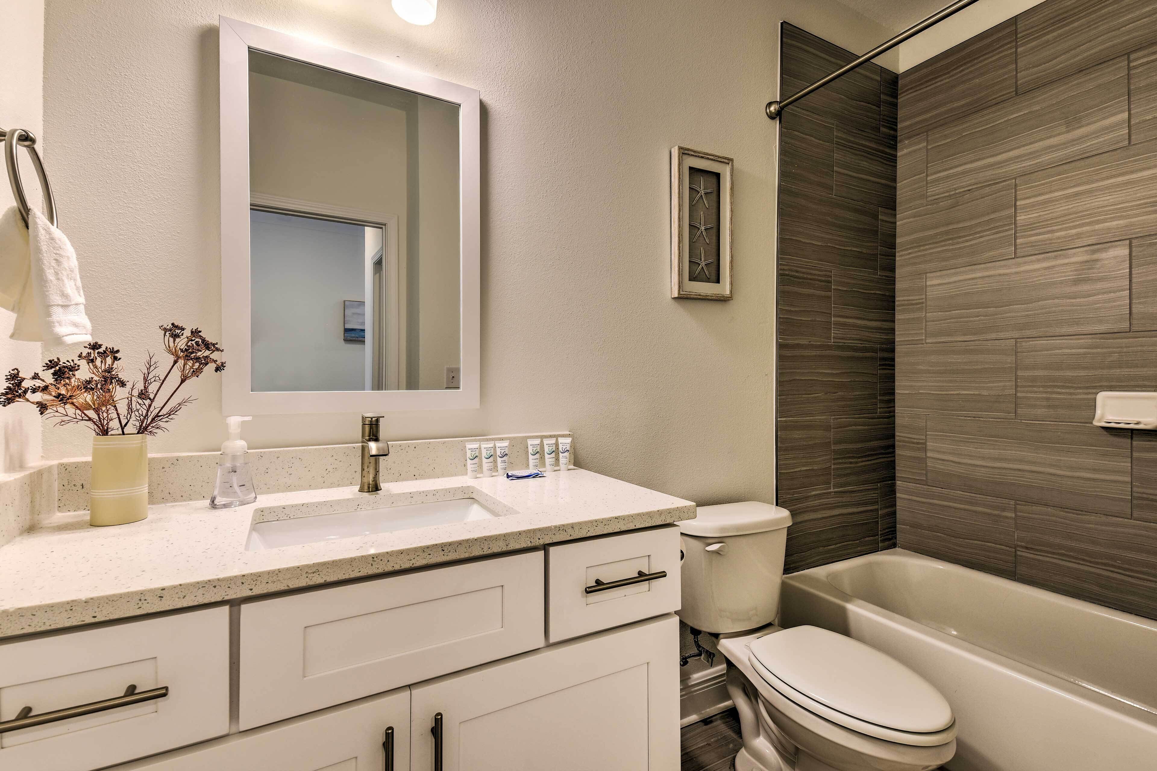 A modern bathroom with a white sink, mirror, and toilet.