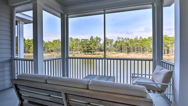 A covered porch with a bench and a table, overlooking a lake and trees. - Santa Rosa Beach Vacation Rental Near Ocean! (Santa Rosa Beach)