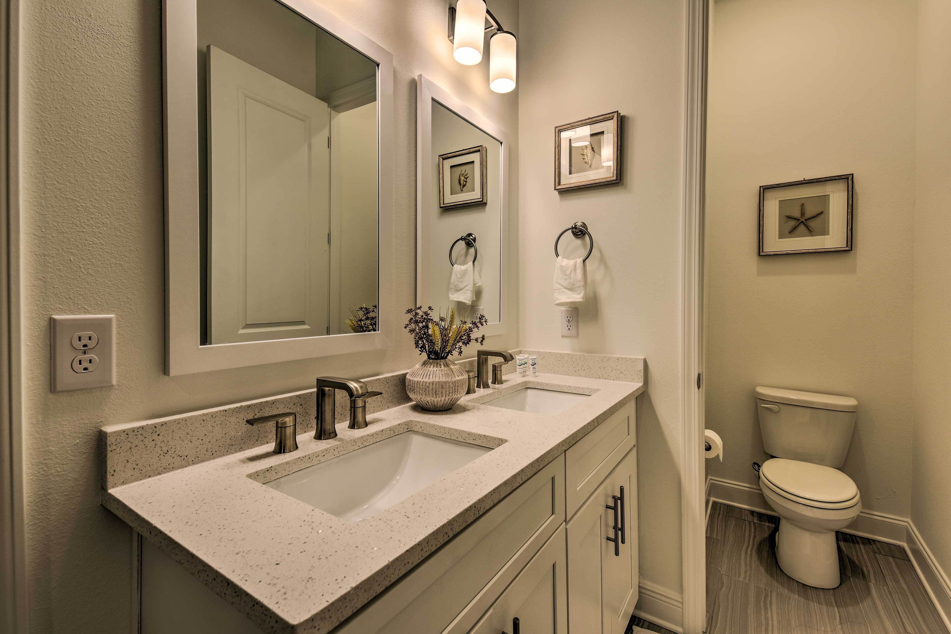 A bathroom with a double sink, a large mirror, and a toilet.