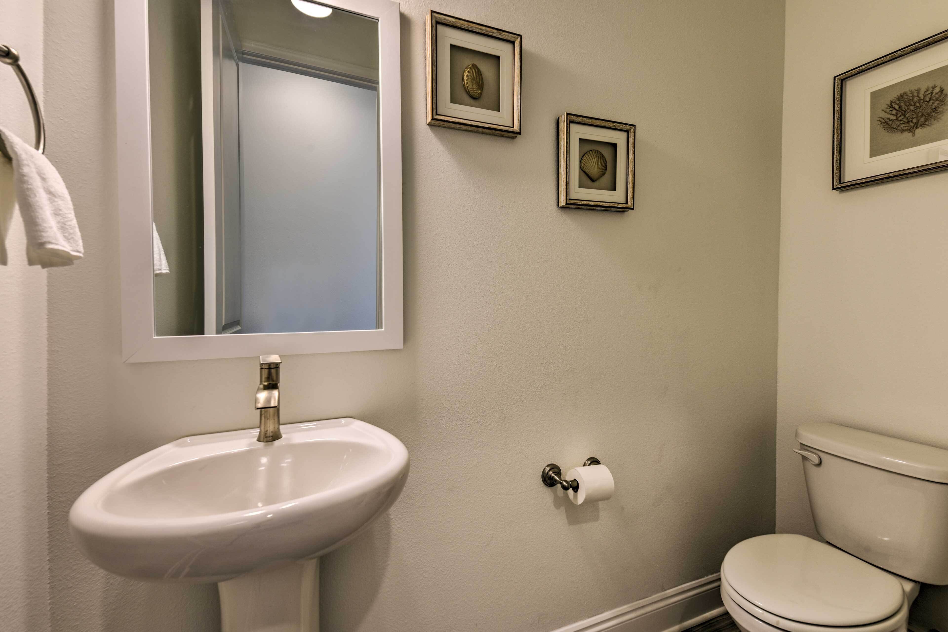 Ein Badezimmer mit Waschbecken, Toilette und gerahmten Bildern an der Wand.
