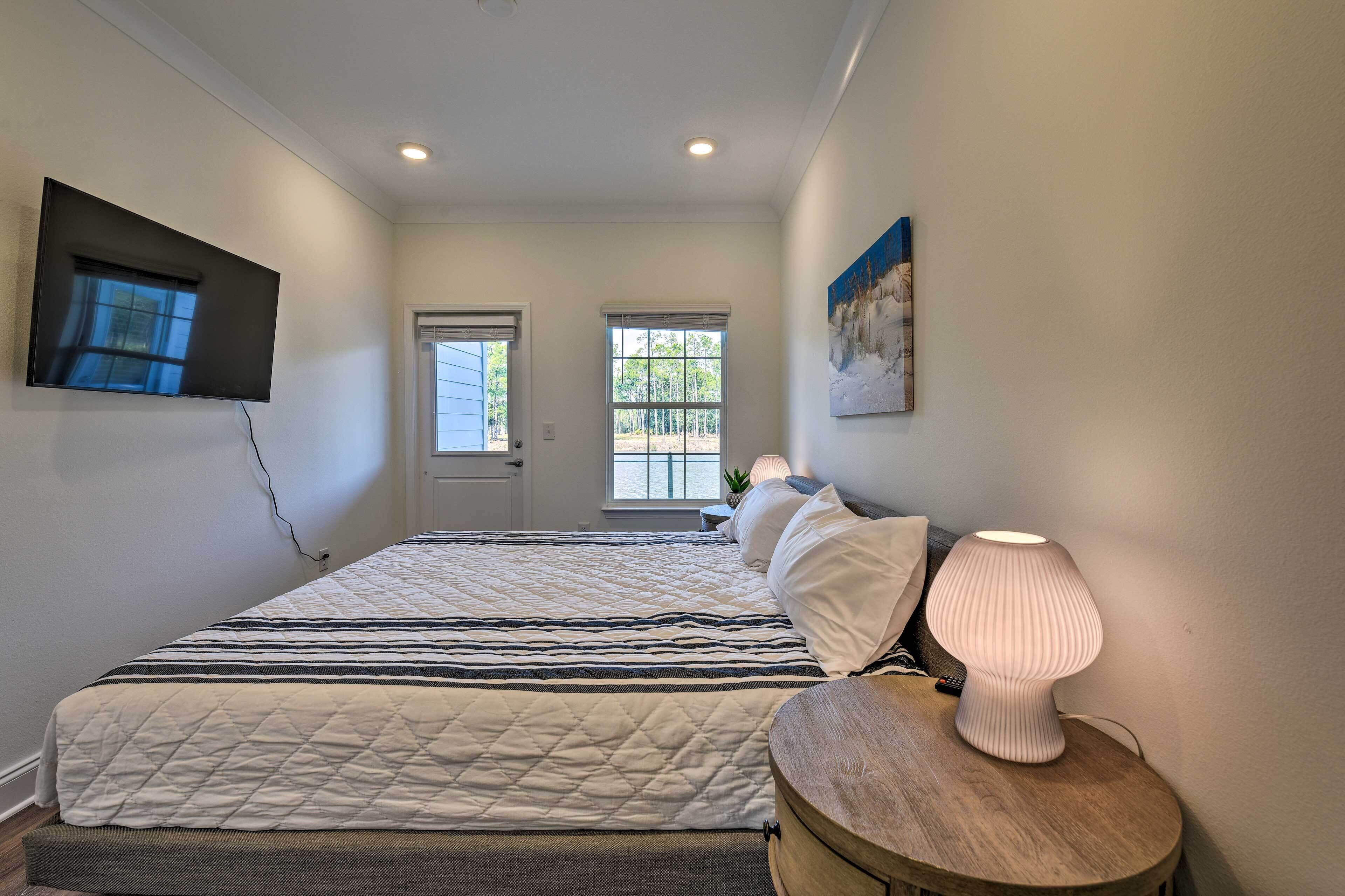 A bedroom with a large bed, bedside lamp, and a TV mounted on the wall.