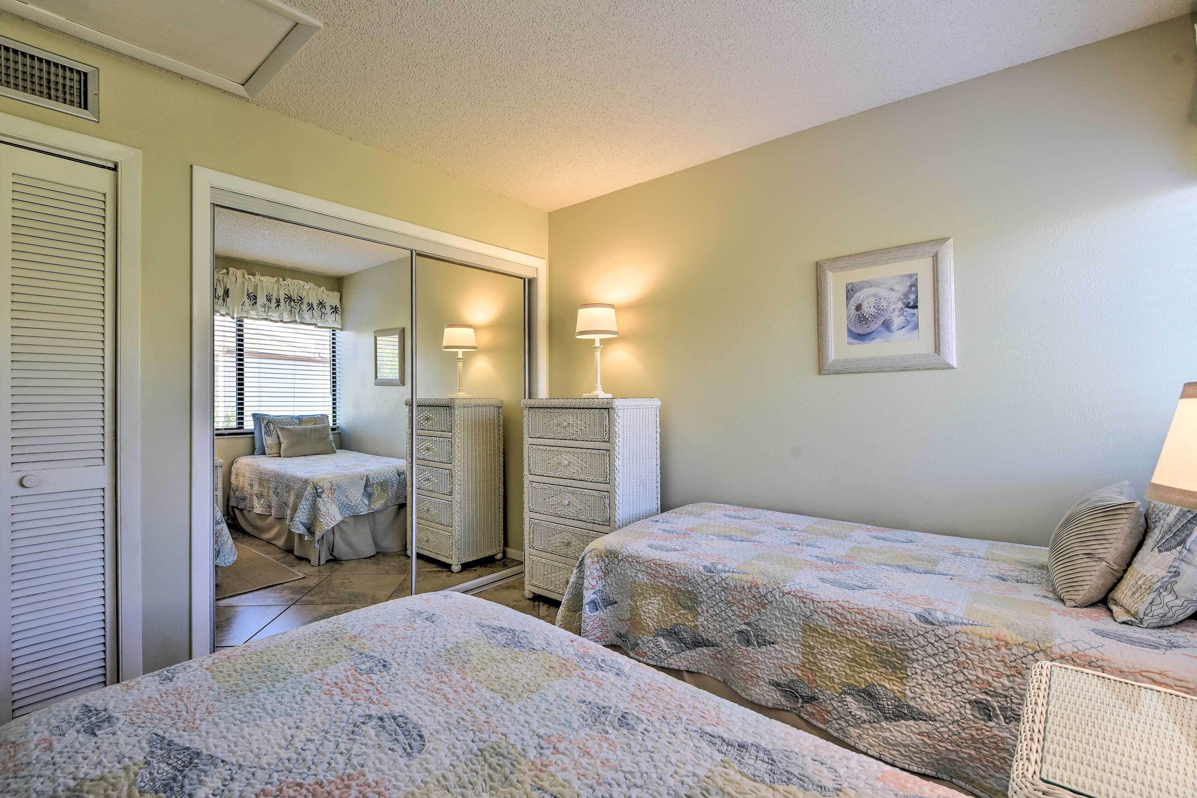 A bedroom with two beds, a dresser, and a mirror.