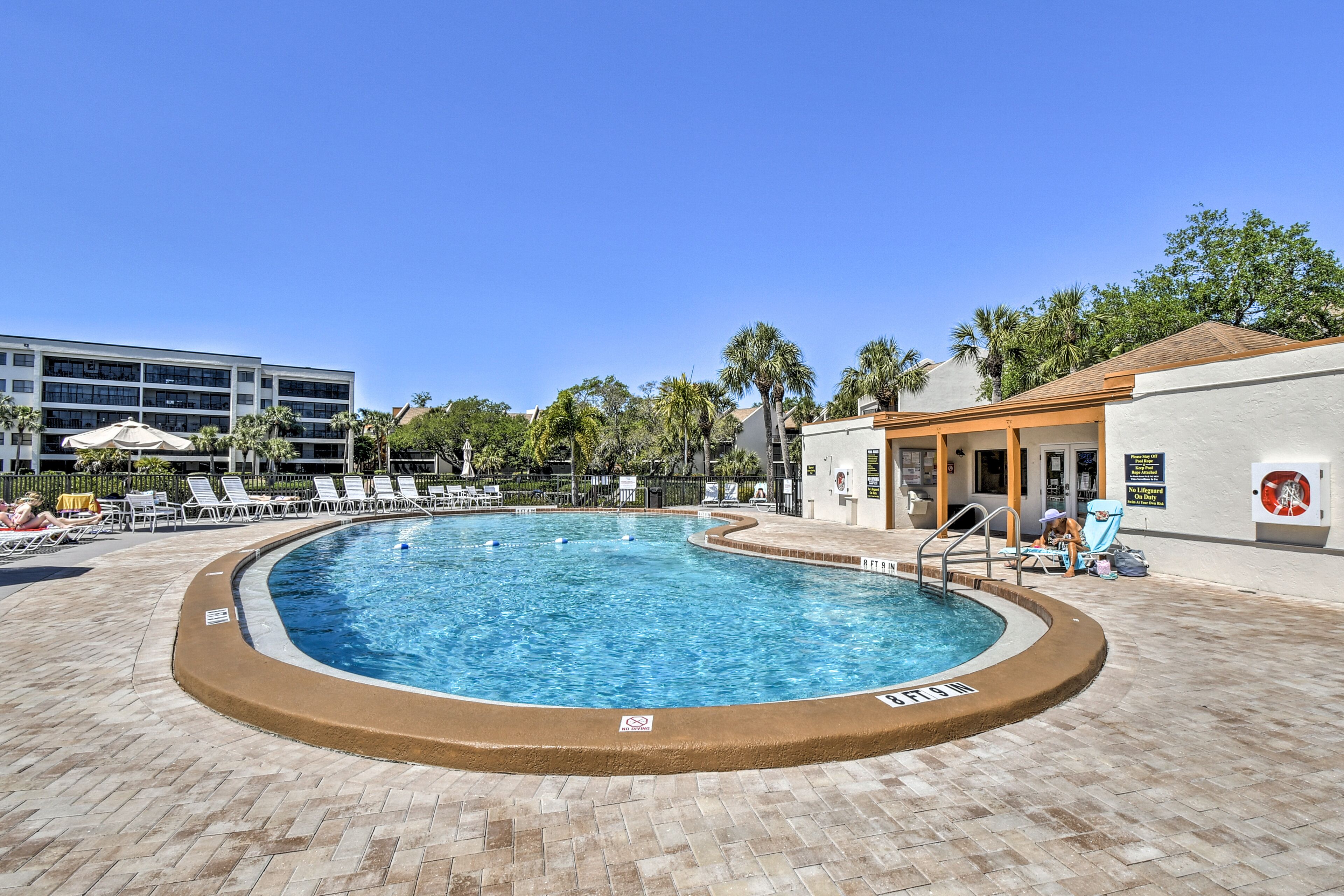 A swimming pool with lounge chairs and a building in the background.