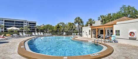 A swimming pool with lounge chairs and a building in the background.