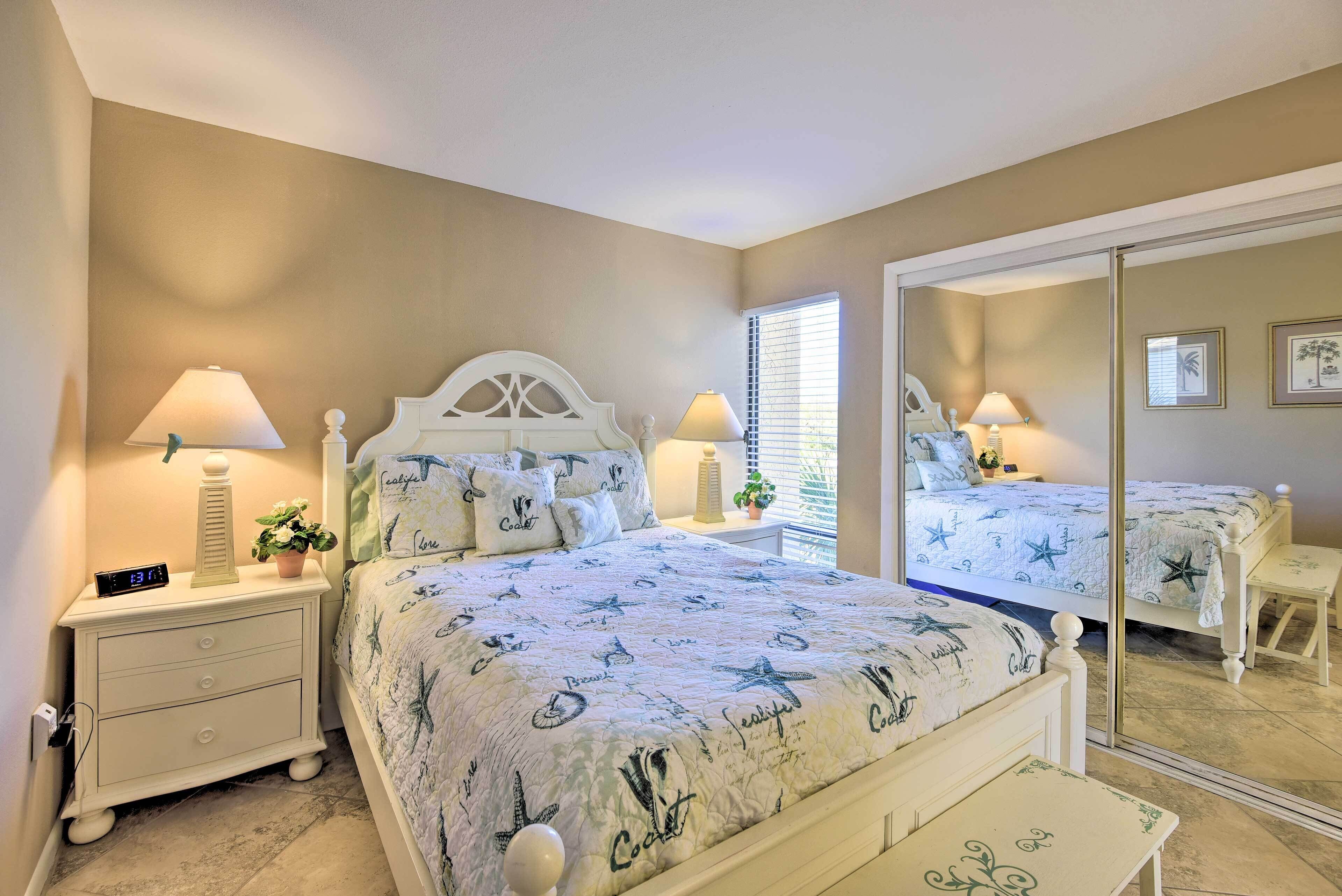 A bedroom with a bed, nightstands, a mirror, and a window with blinds.