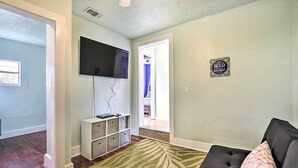 A living room with a flat-screen TV mounted on the wall, a black sofa, and a patterned rug. - Centrally Located Home - 7 Miles to Siesta Key! (Sarasota)