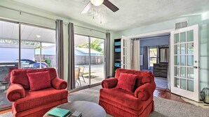 A spacious living room with two red sofas, a coffee table, and a ceiling fan. - Centrally Located Home - 7 Miles to Siesta Key! (Sarasota)