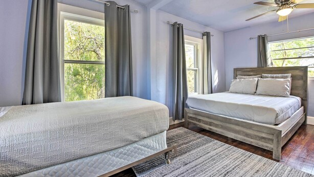A bedroom with two beds, a ceiling fan, and large windows with curtains. - Centrally Located Home - 7 Miles to Siesta Key! (Sarasota)