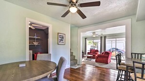 A spacious living area with a wooden dining table, grey upholstered chairs, a ceiling fan, and a view to the outside. - Centrally Located Home - 7 Miles to Siesta Key! (Sarasota)