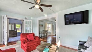 A spacious living room with a red sofa, a coffee table, and a ceiling fan. - Centrally Located Home - 7 Miles to Siesta Key! (Sarasota)