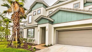 A modern two-story house with a garage, a well-maintained lawn, and a palm tree. - Home w/ Private Pool & Spa: 8 Mi to Disney (Kissimmee)