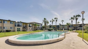 A swimming pool with a 8 ft depth marker, surrounded by a concrete deck, with a building complex in the background. - Sunny Florida Condo: 4 Mi to Gulf Islands Seashore (Fort Walton Beach)