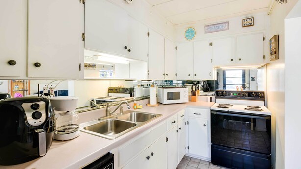 A kitchen with white cabinets, a microwave, a stove, and a coffee maker. - Sunny Florida Condo: 4 Mi to Gulf Islands Seashore (Fort Walton Beach)