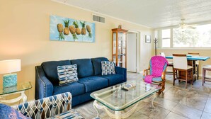 A living room with a blue sofa, patterned armchairs, a glass coffee table, and a dining area with a wooden table and chairs. - Sunny Florida Condo: 4 Mi to Gulf Islands Seashore (Fort Walton Beach)