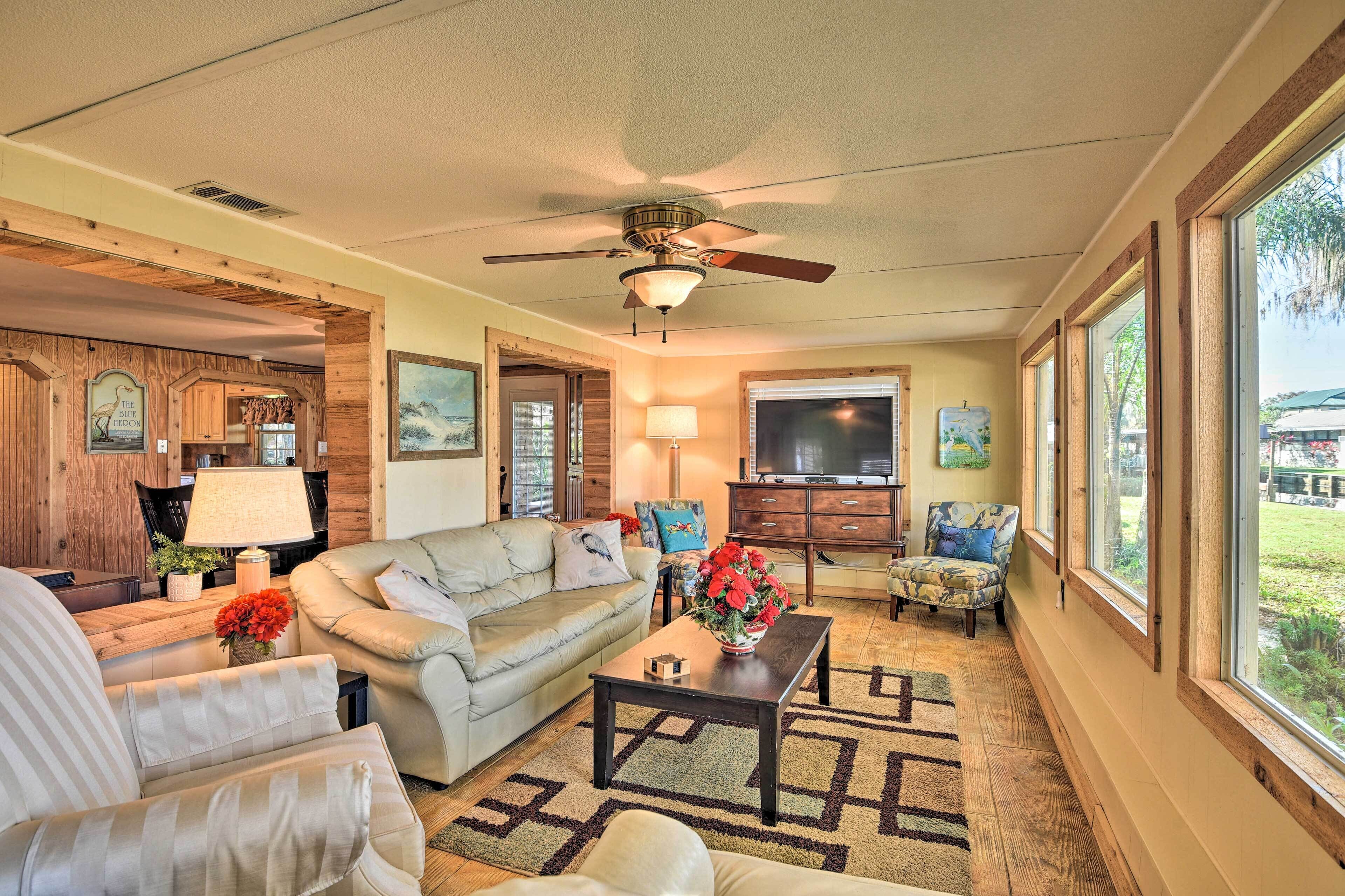 A spacious living room with a ceiling fan, a large window, and a television.