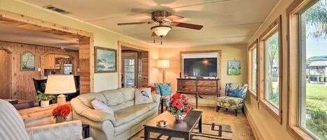 A spacious living room with a ceiling fan, a large window, and a television.