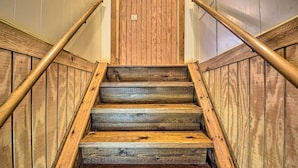 A wooden staircase with a handrail, leading to a door with a light switch. - St Johns River Canal Home w/ Grill! (Crescent City)