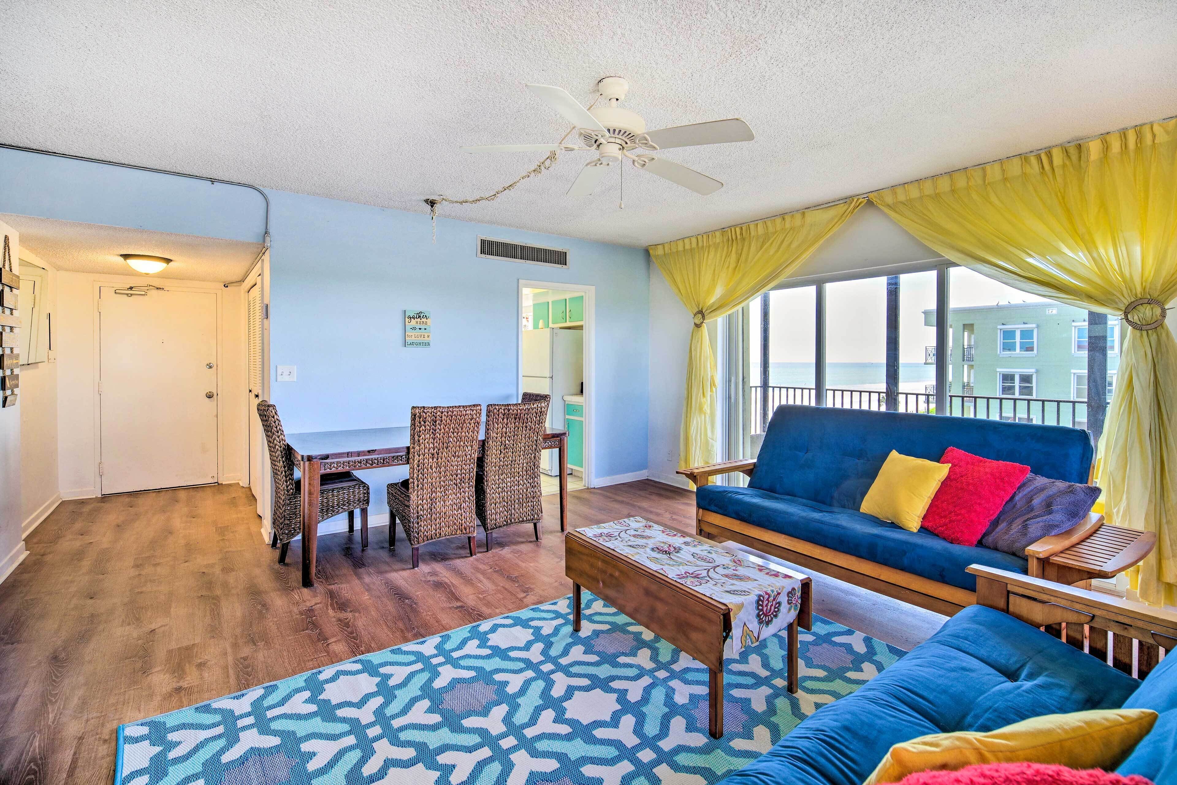 A living room with a blue sofa, yellow curtains, and a view of a building across the street.