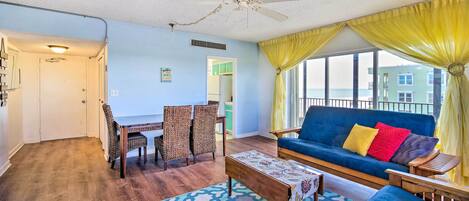 A living room with a blue sofa, yellow curtains, and a view of a building across the street.