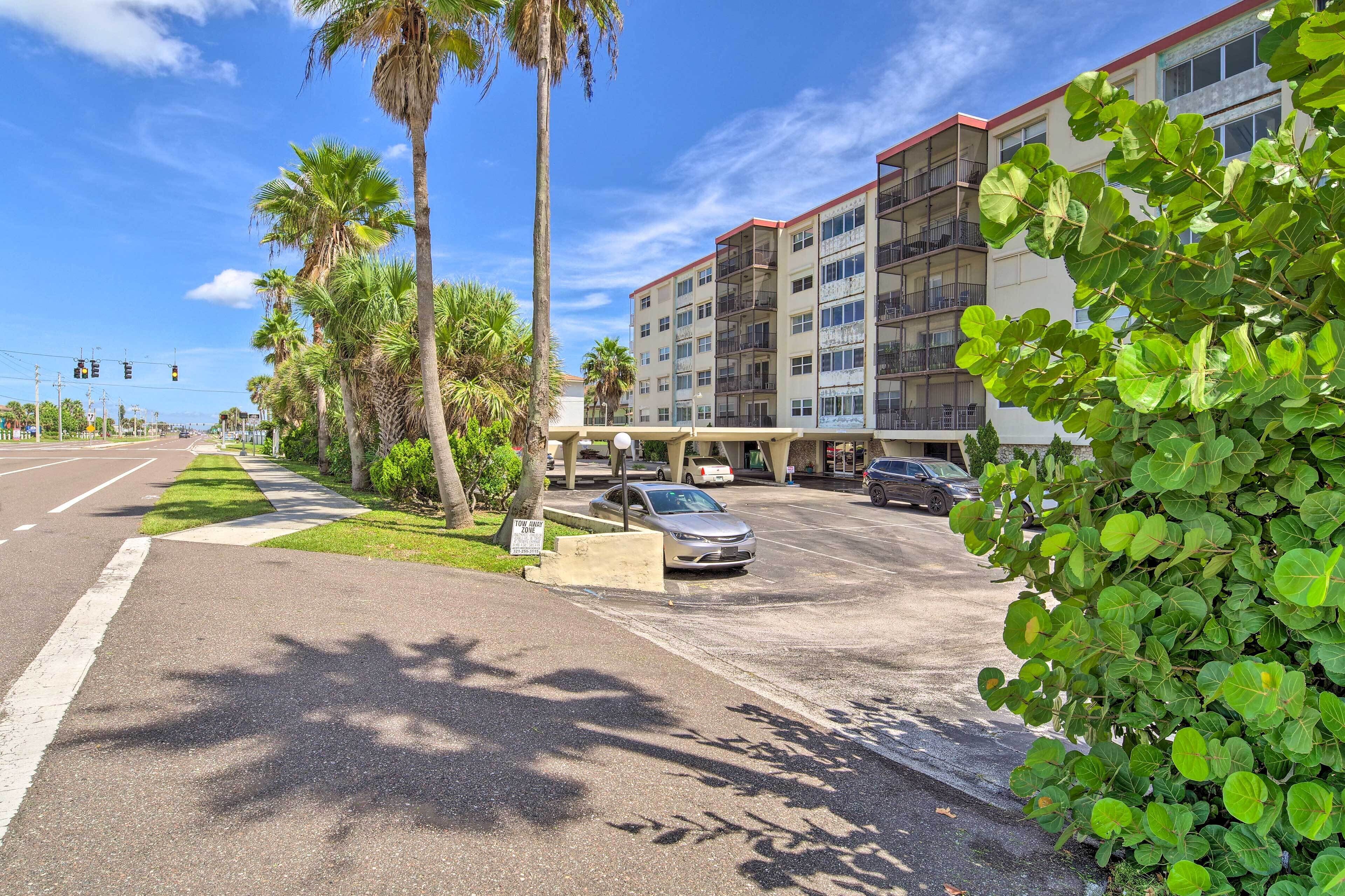 Ein mehrstöckiges Hotel mit Parkplatz, Palmen und blauem Himmel.