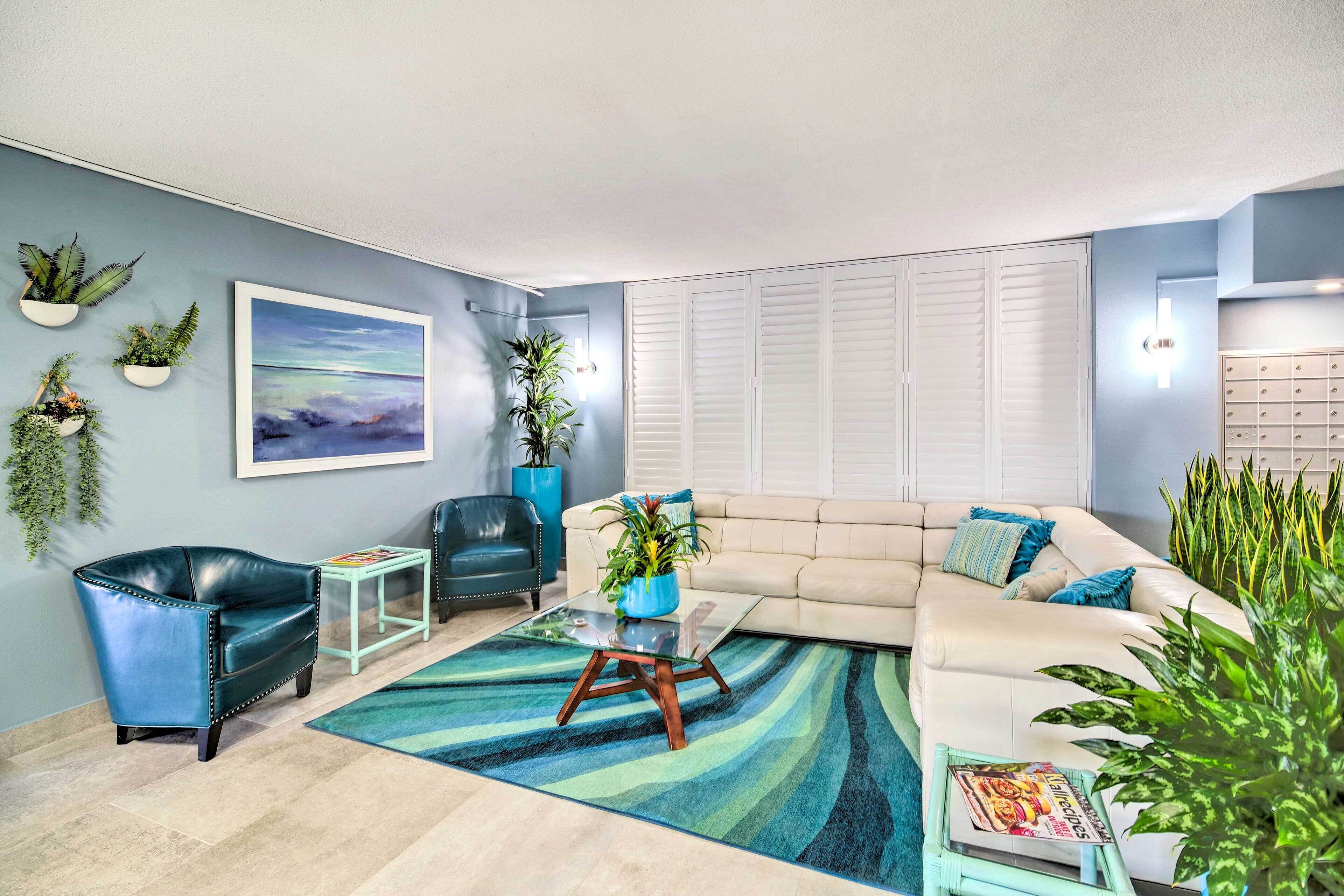 A living room with a sofa, two armchairs, a coffee table, and several potted plants.