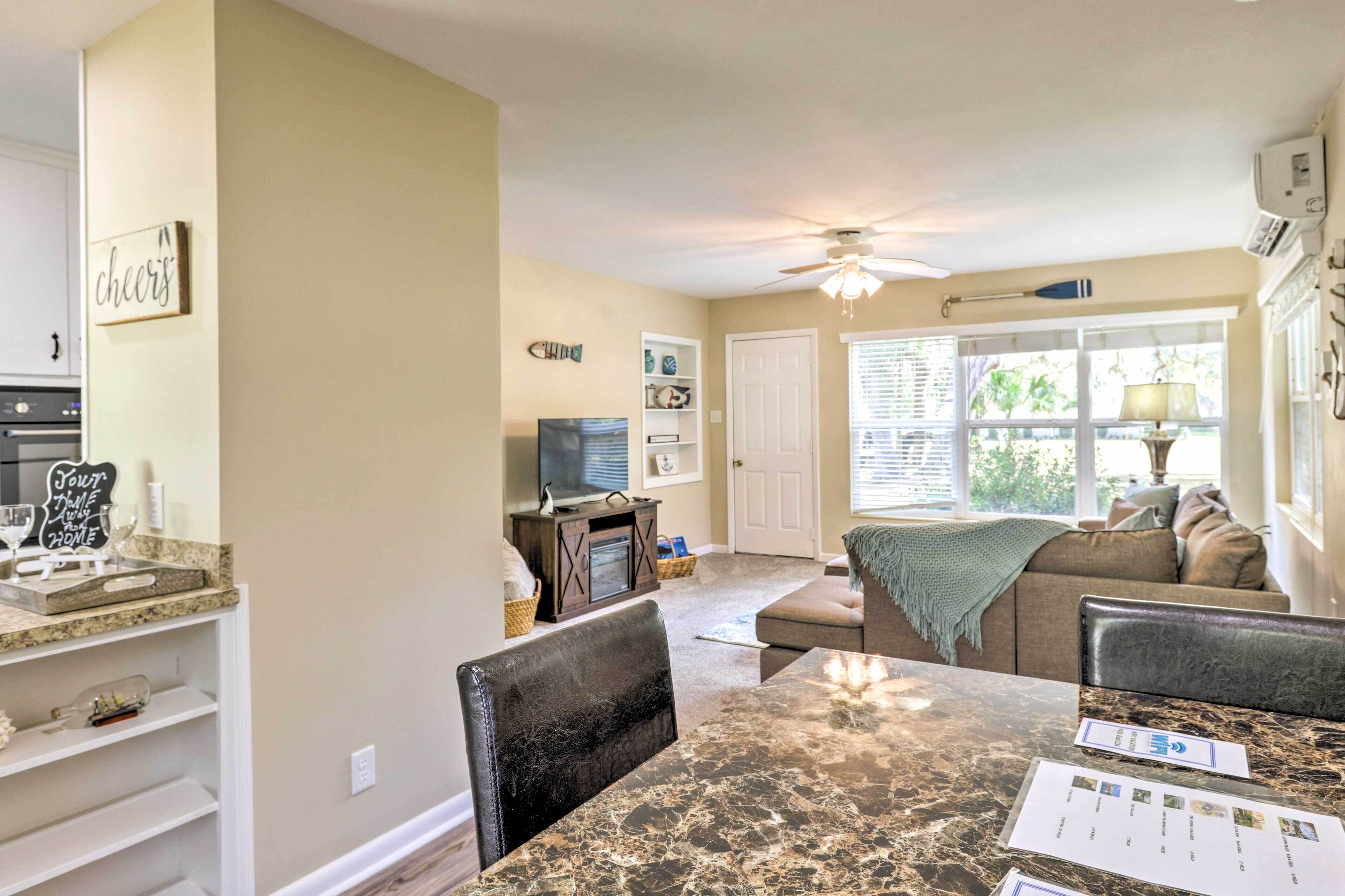 A spacious living area with a dining table, comfortable seating, a television, and a ceiling fan.