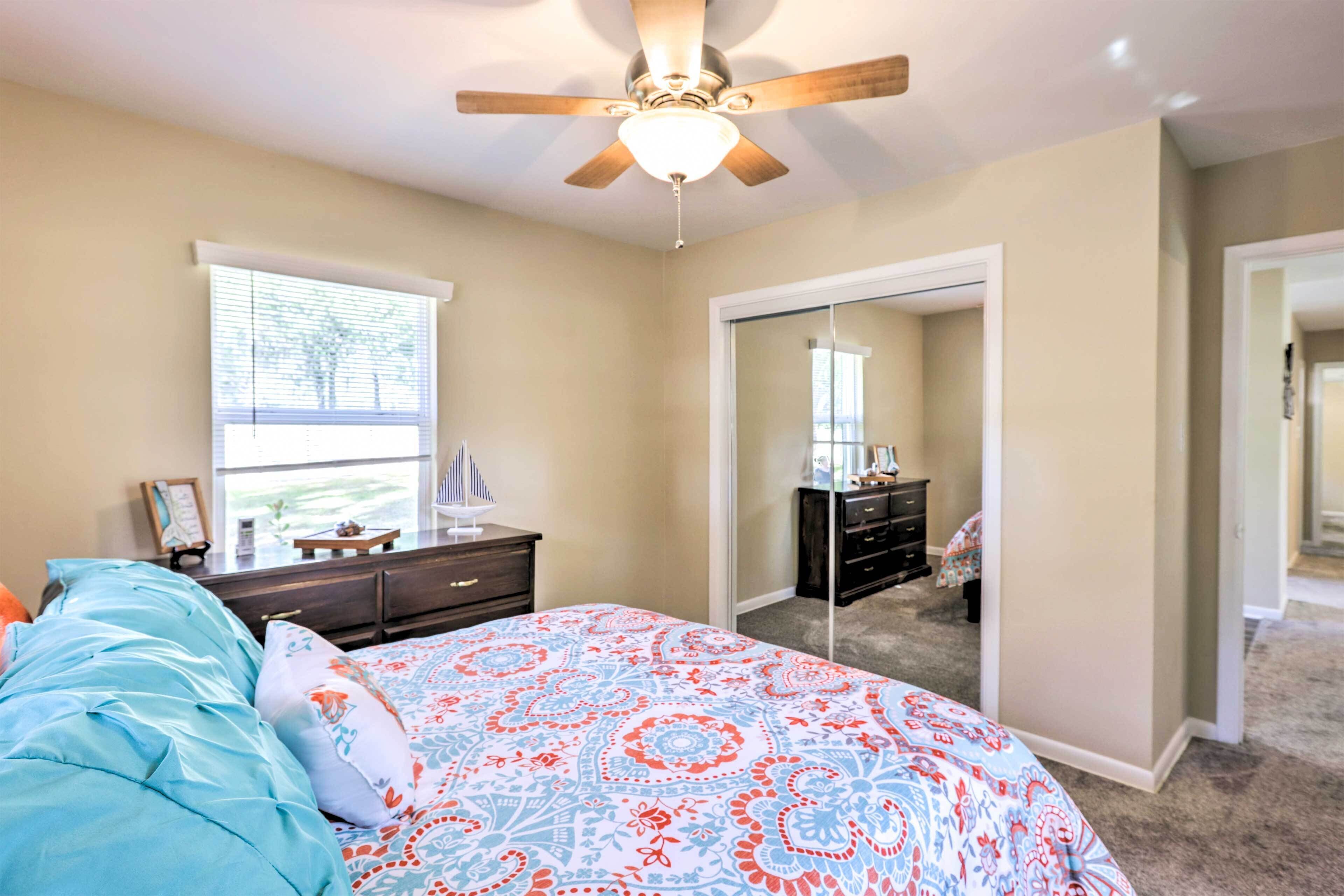 A bedroom with a bed, dresser, and a ceiling fan.