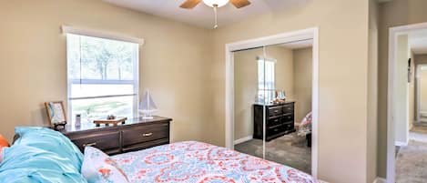 A bedroom with a bed, dresser, and a ceiling fan.