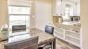 A kitchen with white cabinets, a granite countertop, and a microwave.