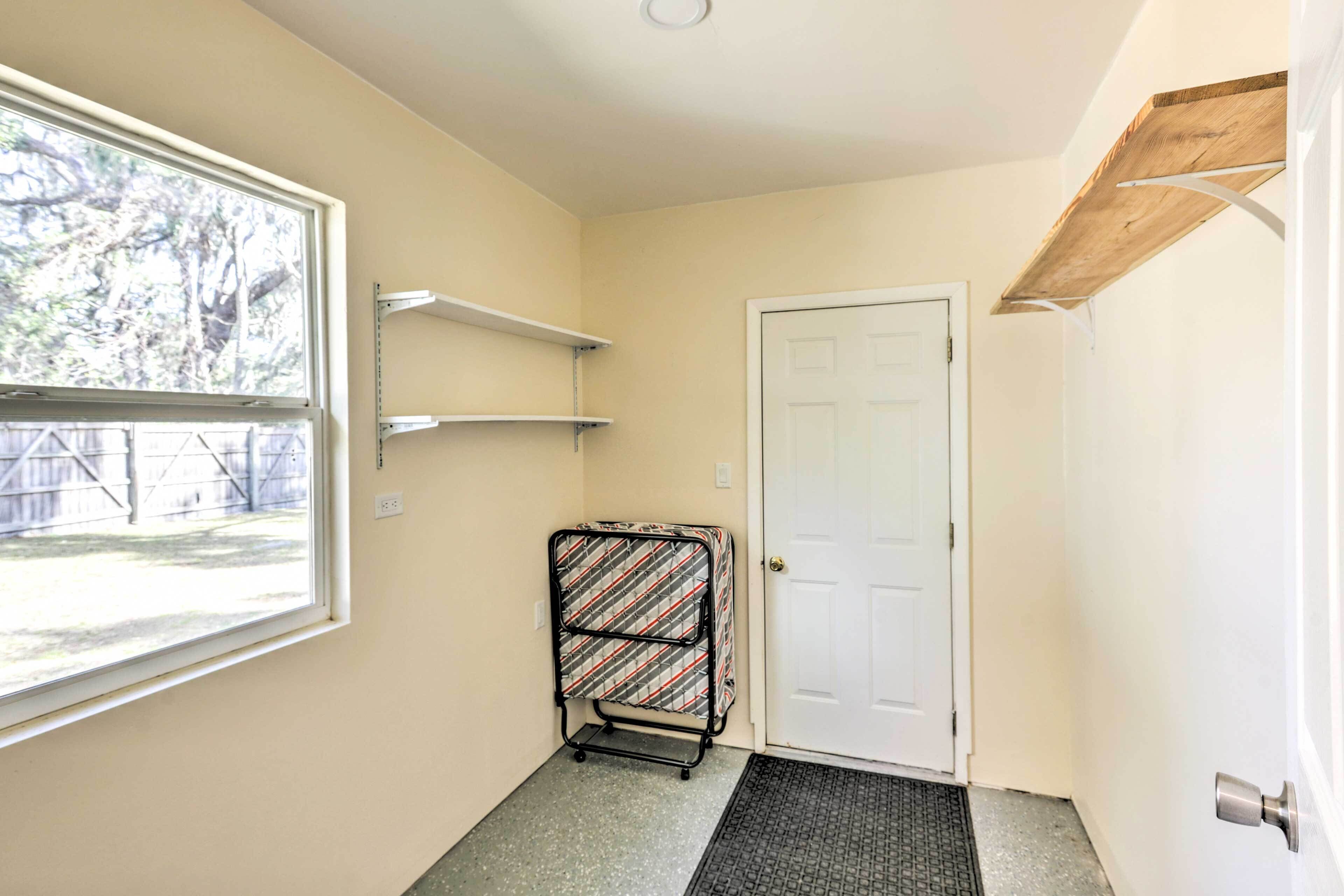 A hallway with a door, a window, a metal rack, and a shelf.