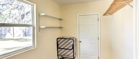 A hallway with a door, a window, a metal rack, and a shelf.