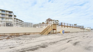 A beachfront hotel with a sandy beach, a wooden staircase, and a building with multiple balconies. - Beachfront Studio w/ Community Indoor Pool! (Daytona Beach)