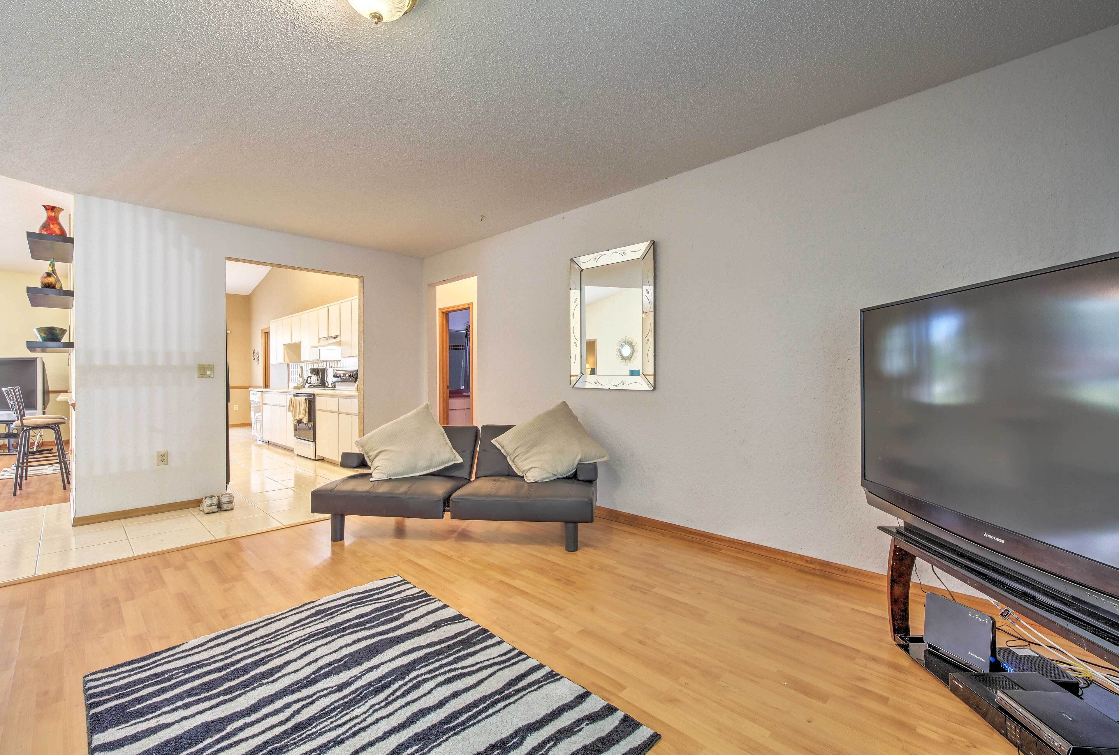 A modern living room with a flat-screen TV, a sofa, and a patterned rug.