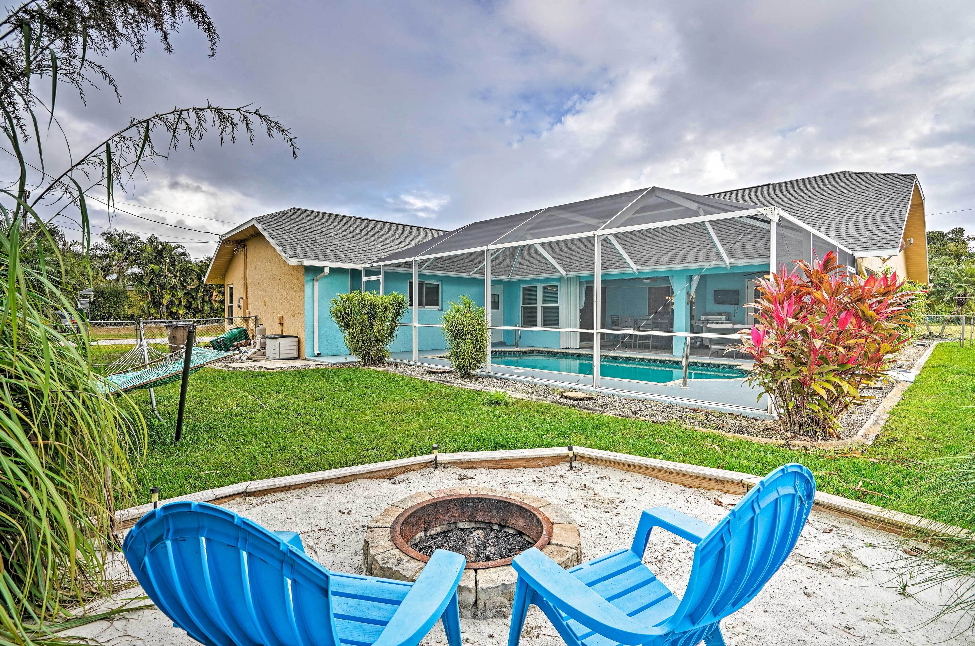 A house with a pool, a fire pit, and blue chairs in the backyard.
