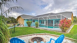 A house with a pool, a fire pit, and blue chairs in the backyard. - Private Yard & Pool: Stunning Cape Coral Getaway! (Cape Coral)