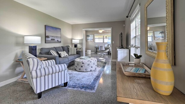 A living room with a sofa, ottoman, striped armchair, and a large vase on a wooden table. - Tampa Home Near Boat Ramp ~ 10 Mi to Dtwn! (Tampa)