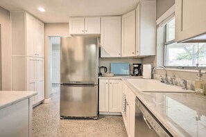 A modern kitchen with white cabinets, a stainless steel refrigerator, a built-in oven, a sink, and a window providing natural light. - Tampa Home Near Boat Ramp ~ 10 Mi to Dtwn! (Tampa)