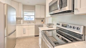 A modern kitchen with white cabinets, a stainless steel refrigerator, a microwave, a toaster, and a double oven. - Tampa Home Near Boat Ramp ~ 10 Mi to Dtwn! (Tampa)