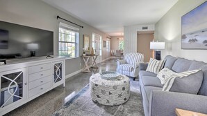 A spacious living room with a grey sofa, a white entertainment unit, and a round ottoman with a nautical theme. - Tampa Home Near Boat Ramp ~ 10 Mi to Dtwn! (Tampa)
