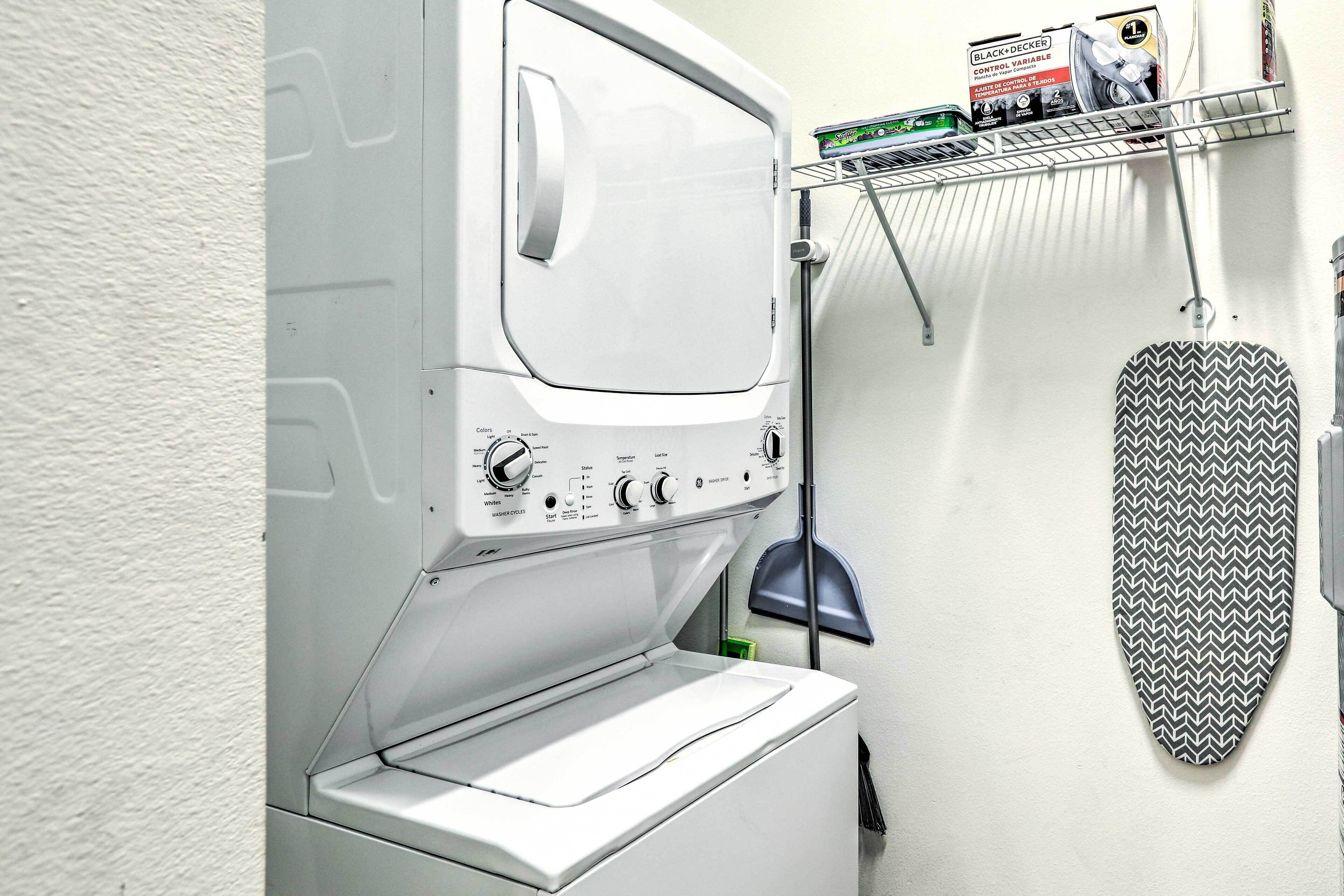 Un lave-linge et un sèche-linge à chargement frontal, dotés d’un panneau de commande, d’une étagère pour le linge et d’une planche à repasser escamotable.