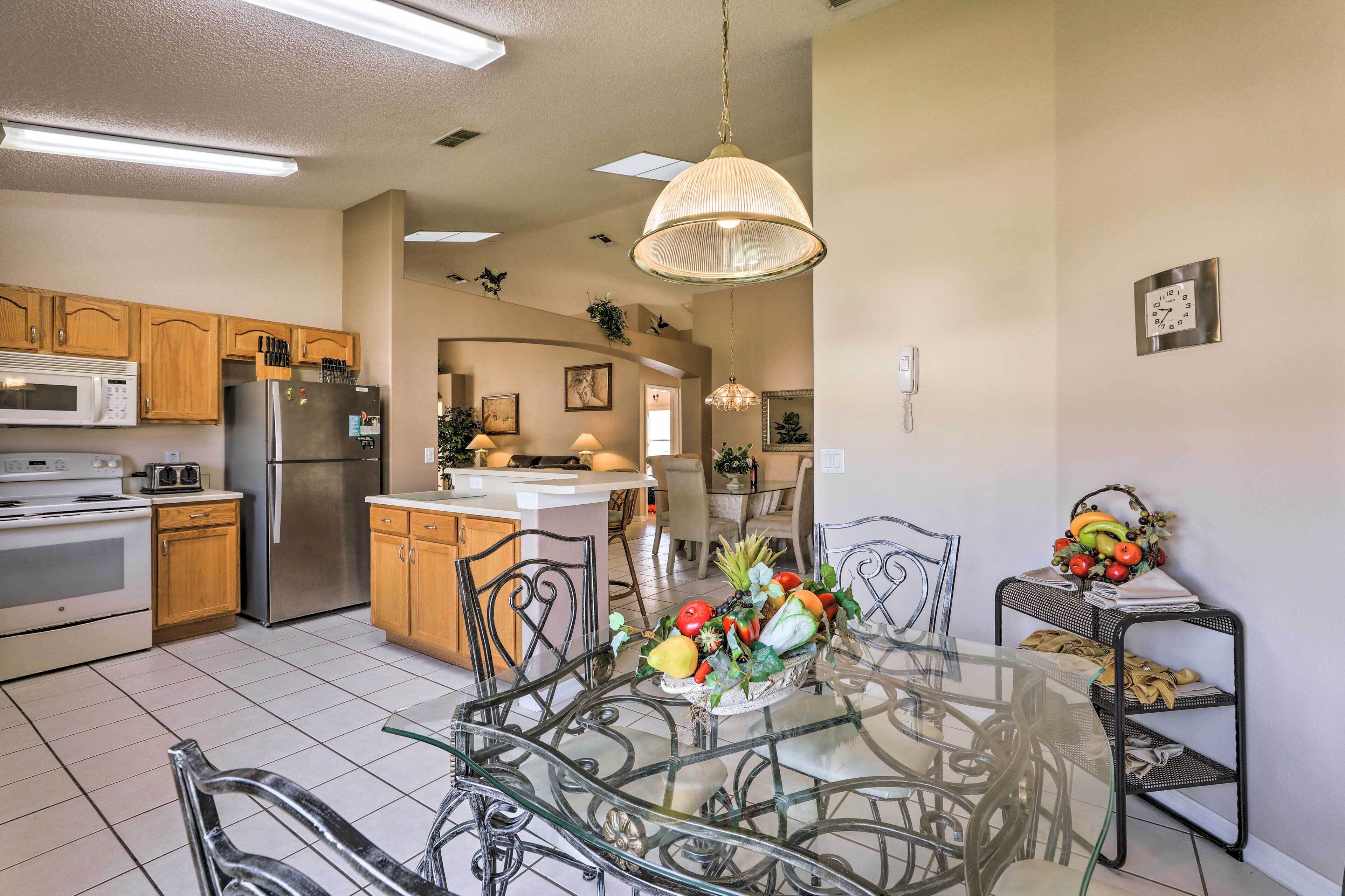 A modern kitchen with stainless steel appliances, wooden cabinets, and a glass dining table with chairs.